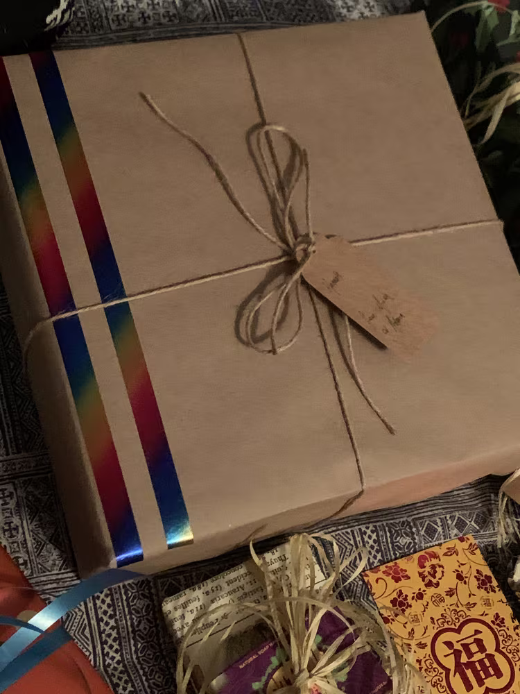 A gift wrapped in plain brown paper with two stripes of washi tape on the left side